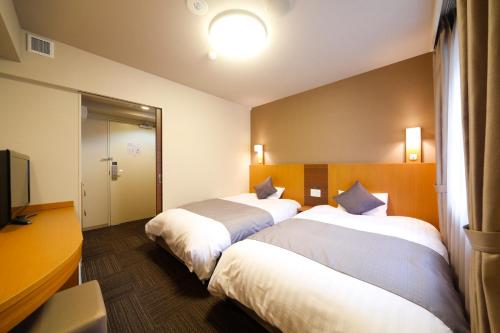 a hotel room with two beds and a television at Dormy Inn Toyama Natural Hot Spring in Toyama