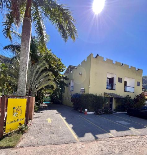 a building with a palm tree next to a parking lot at Pousada Castelinho in São Sebastião