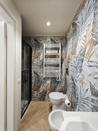 a bathroom with a toilet and tropical wallpaper at La Dimora delle Muse in Sulmona
