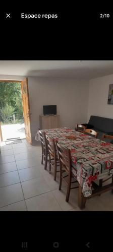 a dining room with a table and chairs and a television at Charmante maison in Sussac