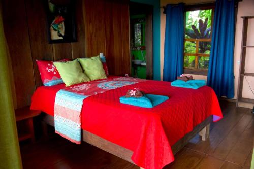 a bedroom with a red bed with two dolls on it at Finca La Puesta del Sol - Miramar de Sierpe in Sierpe