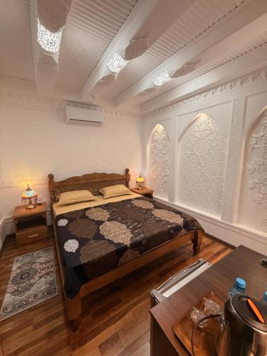 a bedroom with a bed and two tables and two windows at GUZAL Hotel PREMIUM in Bukhara
