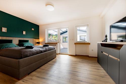 a bedroom with a large bed and a green wall at Ferienhaus Maarruhe in Schalkenmehren