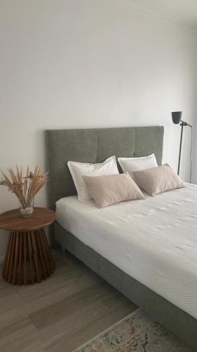 a bed with white sheets and pillows next to a table at Afife Beach Apartment in Afife