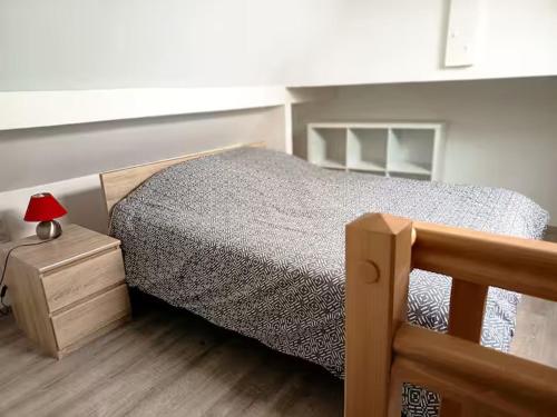 a bedroom with a bed and a table with a lamp at Charmant T2 Cosy - Sous les toits in Luxeuil-les-Bains