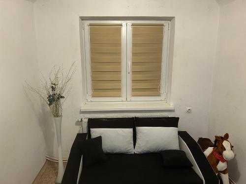 a living room with a black couch and a window at Privát Nikodém in Veľký Slavkov