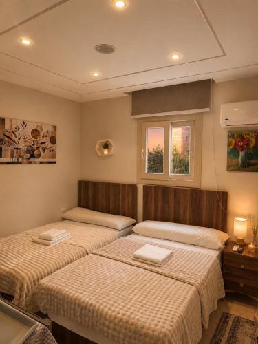 two beds in a room with two windows at Pyramids Green View in Cairo