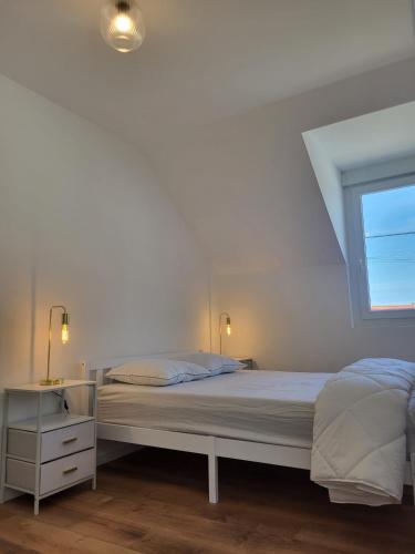 a white bedroom with a bed and a window at petite maison avec jardin in Berck-sur-Mer