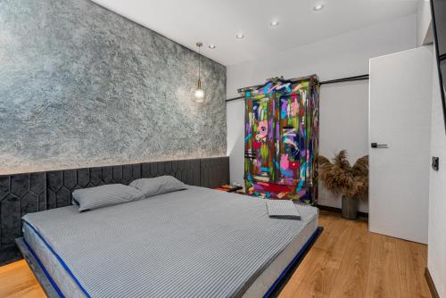 a bedroom with a bed and a painting on the wall at Deribasivska 20 Nice Apartment in Odesa