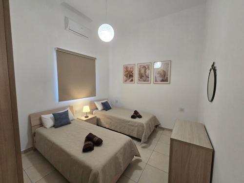 a hotel room with two beds and a table at Arzella Beachfront Guesthouse in Birżebbuġa