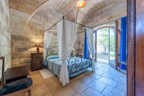 a bedroom with a canopy bed in a stone room at Masseria Copertini in Vernole