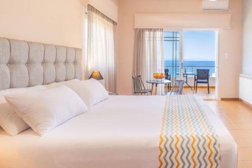 a bedroom with a large bed with a view of the ocean at CHIOS HOTEL in Katarráktis