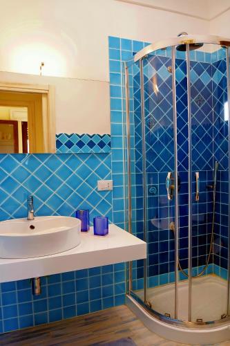 a blue tiled bathroom with a sink and a shower at Dammuso Vento Del Sud in Pantelleria