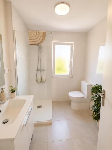 a white bathroom with a toilet and a window at Abuela Maruja - Piso acogedor en Cee, perfecto para desconectar in Cee