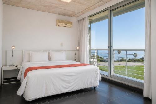a white bedroom with a bed and a large window at Costa Colonia - Riverside Boutique Hotel in Colonia del Sacramento