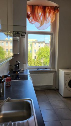 a kitchen with a sink and a large window at Old Town Apartment Opole in Opole
