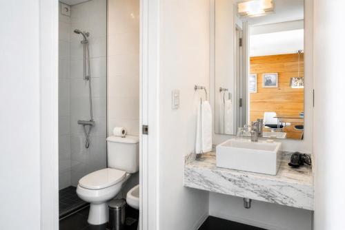 a white bathroom with a toilet and a sink at Costa Colonia - Riverside Boutique Hotel in Colonia del Sacramento