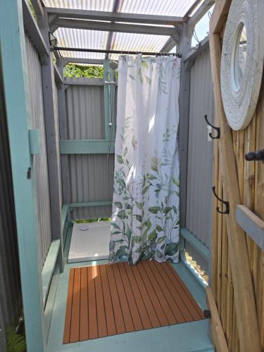 a pergola with a shower curtain on a porch at Dorset Glamping Fields in Corfe Mullen