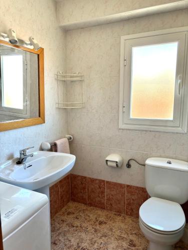 a bathroom with a toilet and a sink and a window at Apartamento vacacional Jávea in Jávea