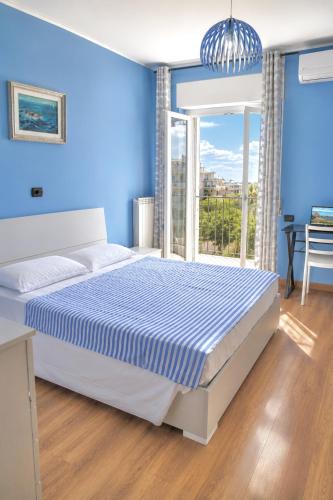 a blue bedroom with a bed and a window at Tari Home Crotone in Crotone