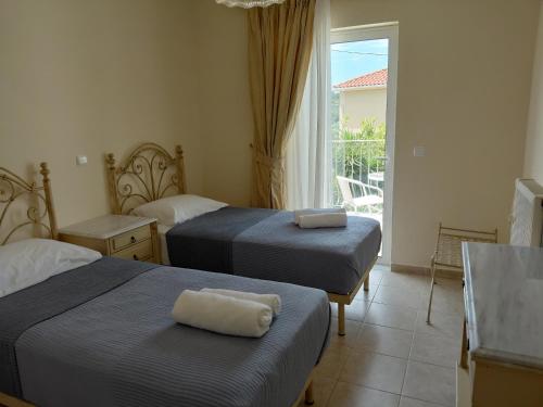a hotel room with two beds and a balcony at Irini's Villa in Argostoli