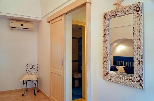 a mirror in a room with a chair and a bedroom at Dammuso Terra e Mare in Kamma