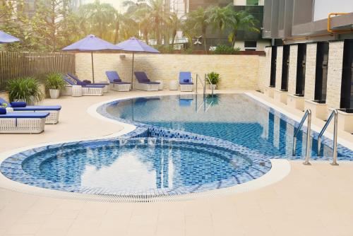 a swimming pool with chairs and umbrellas in a building at Novotel Suites Hanoi in Hanoi