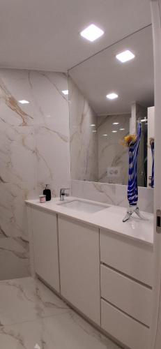 a white bathroom with a sink and a mirror at Solar da Pedra in Paços de Ferreira