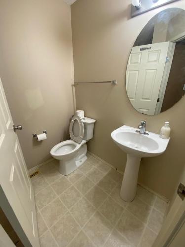 a bathroom with a toilet and a sink and a mirror at Modern Basement Suit west side with Room 4 in Edmonton