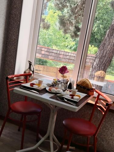 a breakfast table with two red chairs and a window at RamRamay in Qax