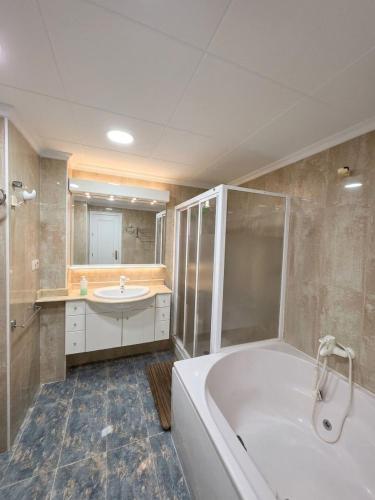 a large bathroom with a tub and a sink at Ático vistas al mar in Cullera