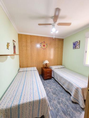 a bedroom with two beds and a ceiling fan at Ático vistas al mar in Cullera