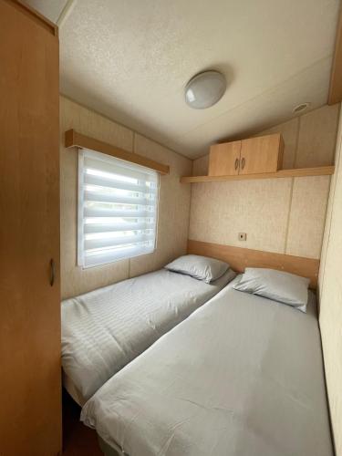 two beds in a small room with a window at Bungalow Katalina in Bourbourg