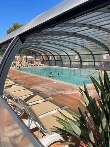 a swimming pool with lounge chairs in a building at Camping Canet plage mobilhome 4 ou 6 personnes in Canet-en-Roussillon