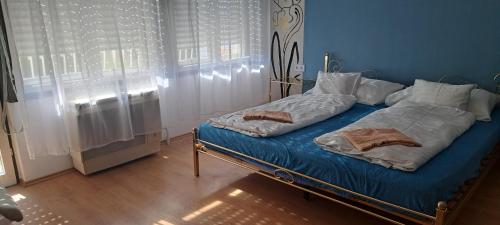 a blue bedroom with a bed with blue sheets and pillows at Bluebird apartman in Zalakaros