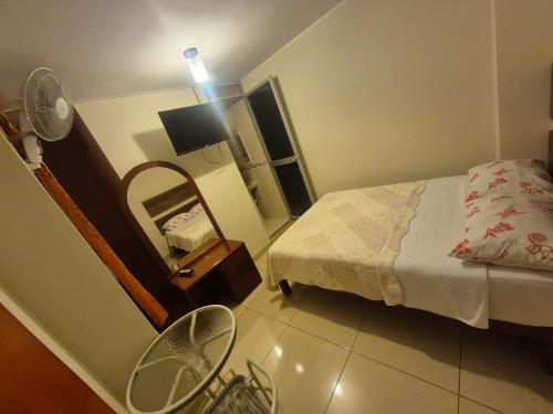 a bedroom with a bed and a mirror and a fan at Hospedaje Valencia in Ica