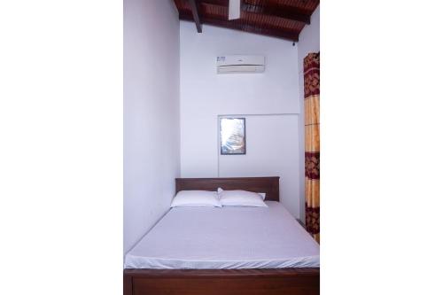 a bedroom with a bed in a white room at minidu resort in Ambalantota