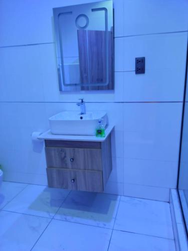 a white bathroom with a sink and a mirror at Apartments 4B Block B in Lagos