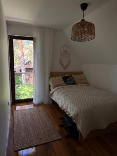 a bedroom with a bed and a large window at Całoroczny Domek nad Jeziorem in Białka