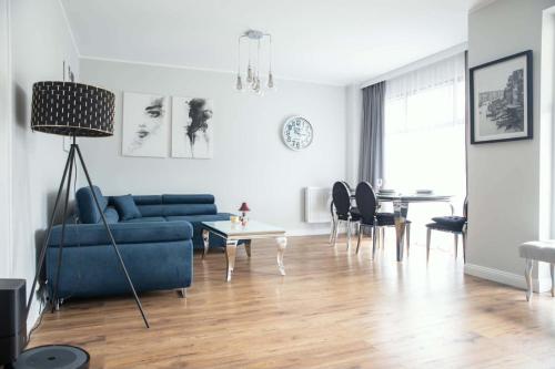 a living room with a blue couch and a table at Apartament Baltic Prestige in Gąski
