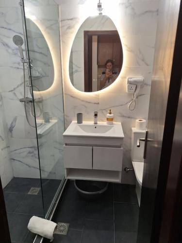 a woman taking a picture of a bathroom with a mirror at Villa Litsa in Ermones