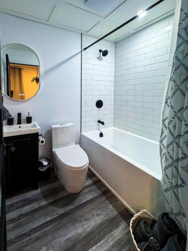 a bathroom with a tub and a toilet and a sink at Studio Moderne Chic Gatineau Ottawa in Gatineau