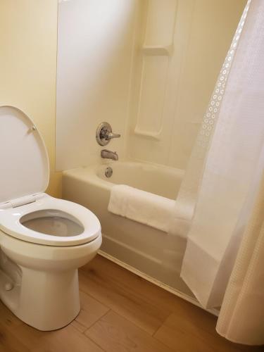 a white bathroom with a toilet and a bath tub at Carolyn Beach Inn in Thessalon