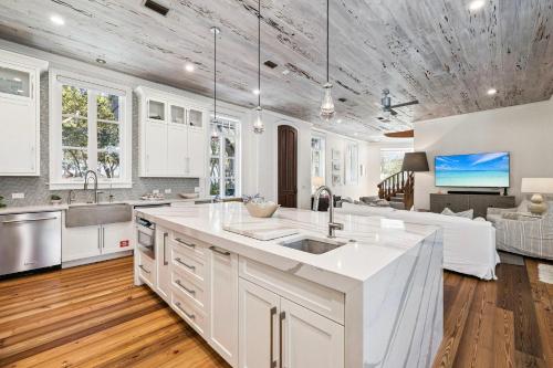 a kitchen with white cabinets and a living room at Serenity Now in Rosemary Beach