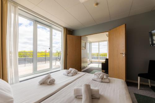 ein Schlafzimmer mit zwei Handtüchern auf einem Bett mit einem großen Fenster in der Unterkunft Meri Seaside Hotel & SPA in Kuressaare