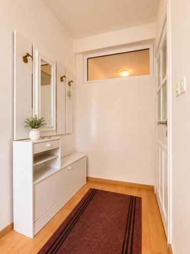 a hallway with white walls and a window and a rug at Bonita Apartments in Mostar