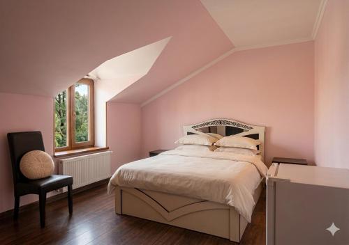 a bedroom with pink walls and a bed and a chair at Hotel Nirvana in Dilijan