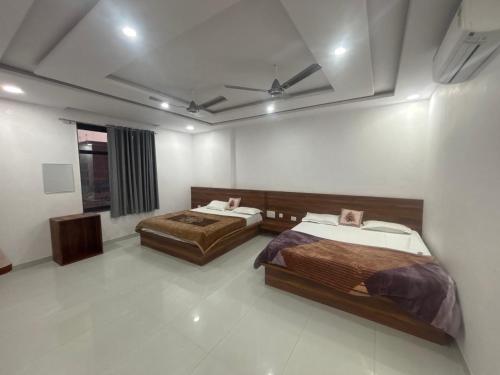 a bedroom with two beds and a ceiling at Lord Krishna hotel in Khātu
