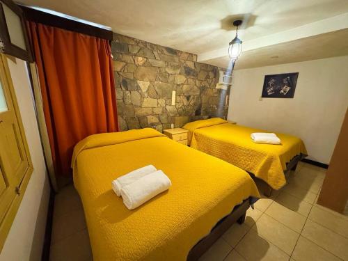 two beds in a room with yellow sheets at Posada "Jardin Huasteca Xilitla" in Xilitla