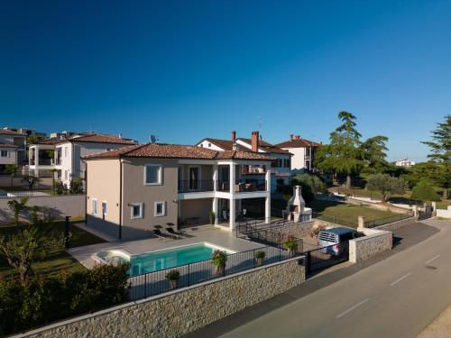 a house with a swimming pool next to a street at Villa Kortus Luxury modern villa near Petram Resort, beach 700m and Adriatic golf resort in Savudrija